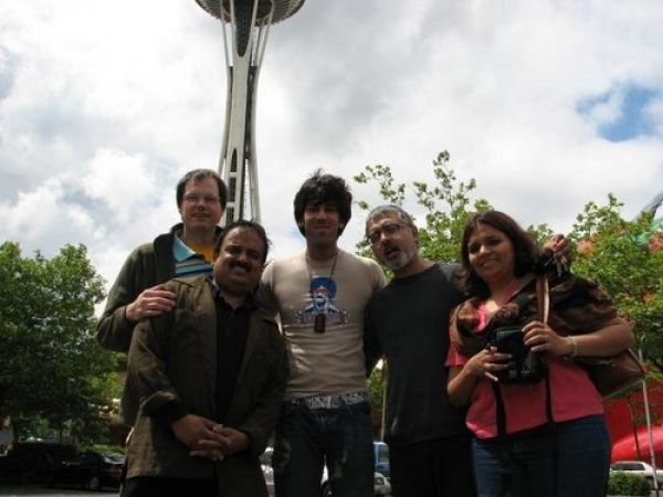 Group of five people standing outdoors with park and tall observation tower in the background.